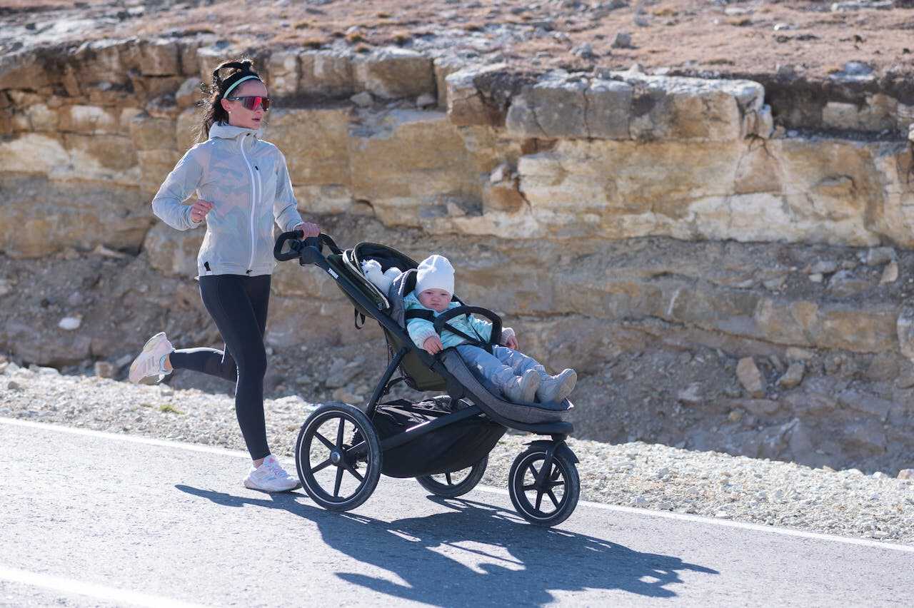 Kvinde der løber med sit barn i en baby jogger