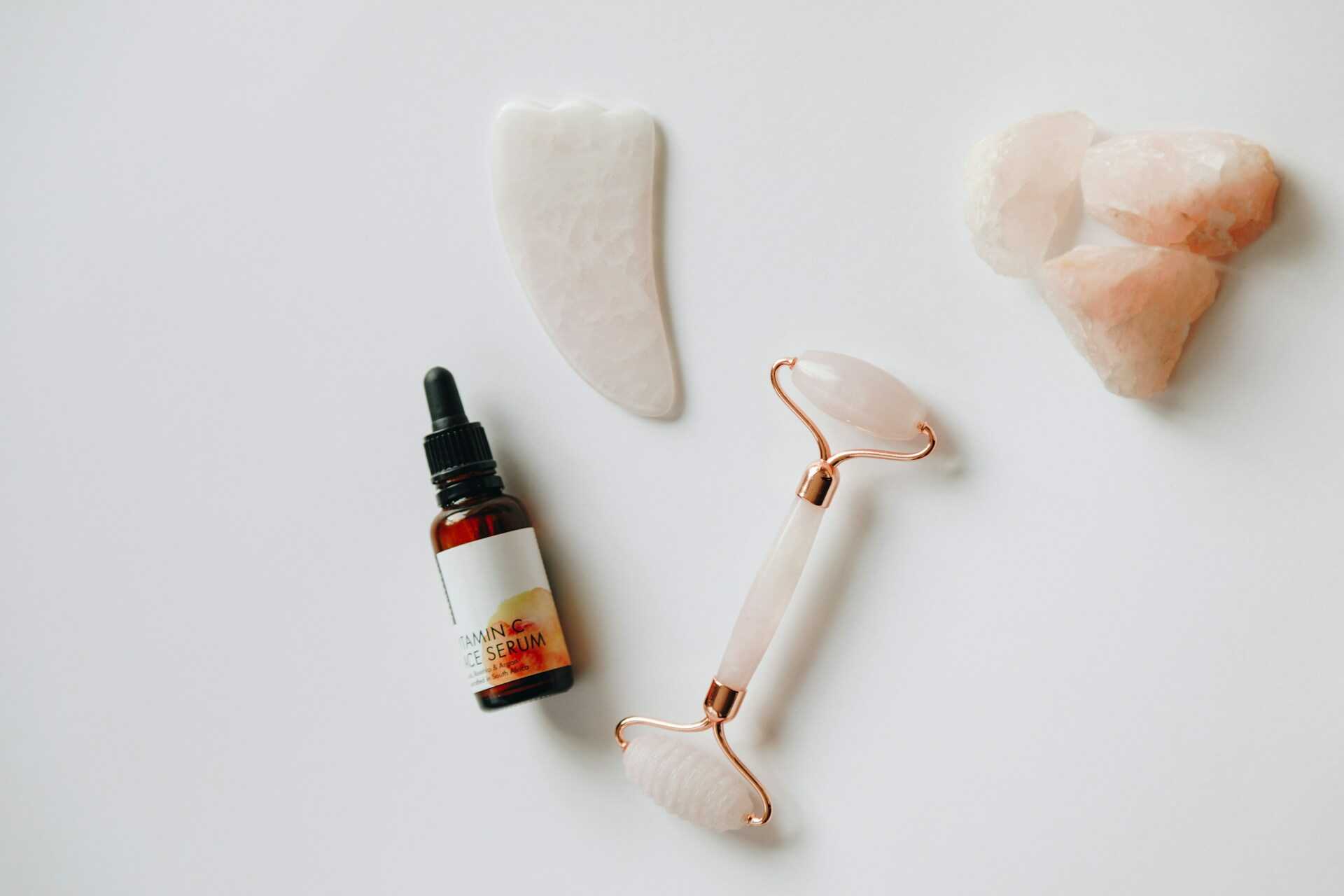 Skin roller, gua sha serum og sten på et bord